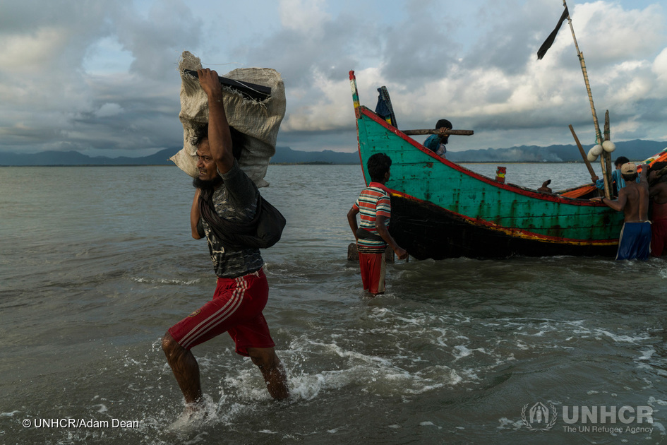 En Rohingya-mand bærer en pakke hen til stranden ved Dakhinpara, Bangladesh. © UNHCR/Adam Dean