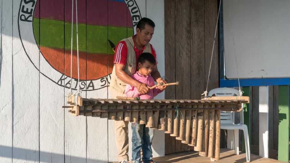 Armando Cuasaluzan Pai, 38, teaches his nephew how to play the marimba - a percussion instrument built from bamboo and traditional to the Awá culture.