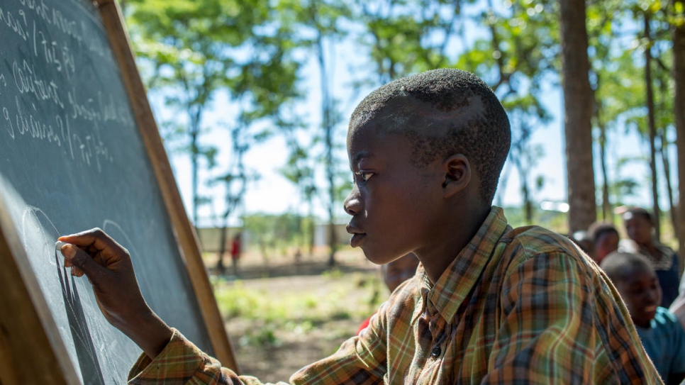Burundi refugee student Richard Nduwimana, 13, writes on the blackboard.