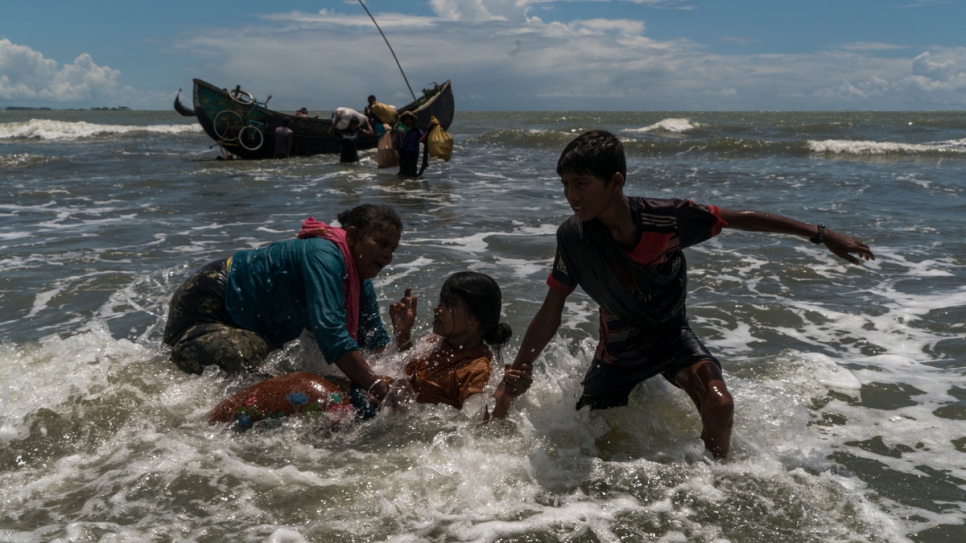 Rohingya refugees scramble off a fishing boat as it nears the beach at Dakhinpara, Bangladesh.