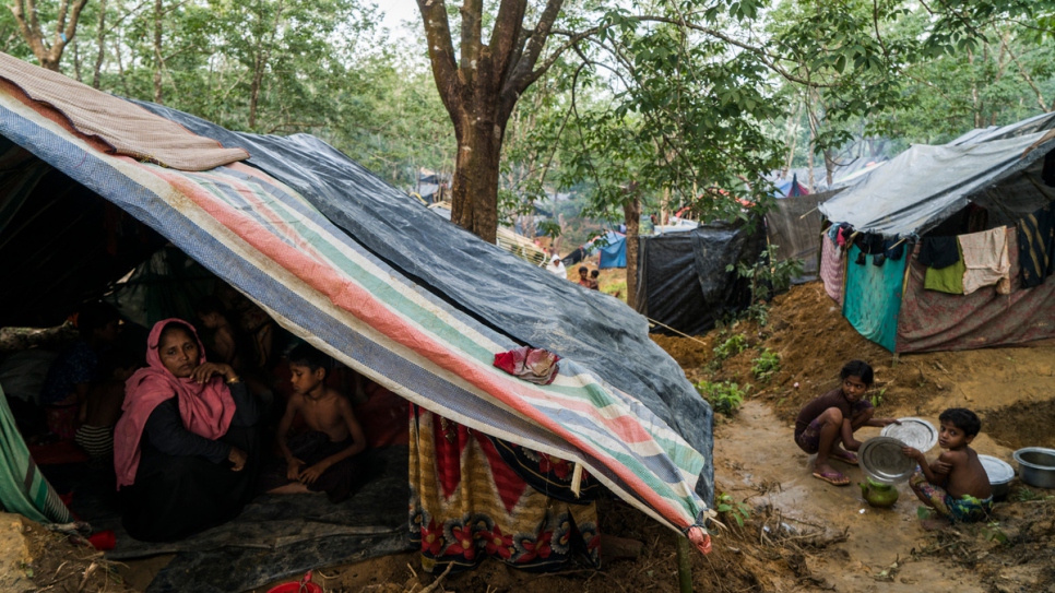 Rohingya refugees from Myanmar shelter under tarpaulin sheets in muddy conditions at an informal settlement for new arrivals, near Kutupalong camp in Bangladesh.