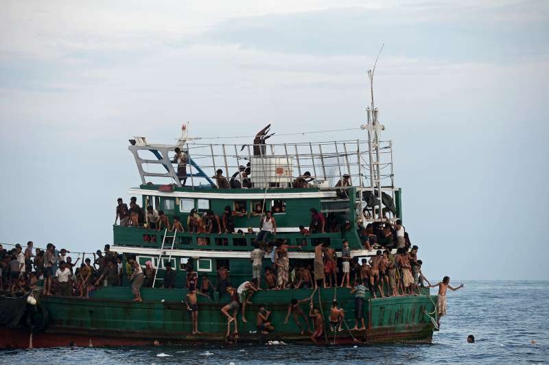 Des réfugiés à la dérive dans la mer d'Andaman recueillent de la nourriture larguée par un bateau de pêche. 