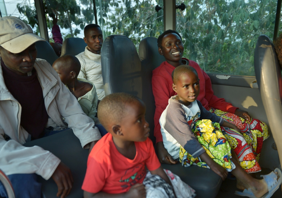 تجلس تشارلين في حافلة استأجرتها المفوضية مع زوجها (خلفها) وطفليهما.