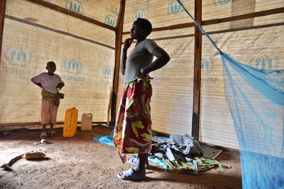 تقف تشارلين في مأواها الجديد مع ابنها في مخيم ماهاما للاجئين.