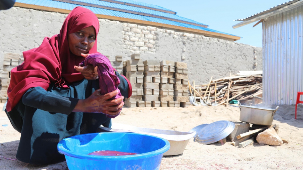 Fadumo essore une pièce de tissus qu'elle est en train de teindre dans son atelier situé sur le toit de la maison. 