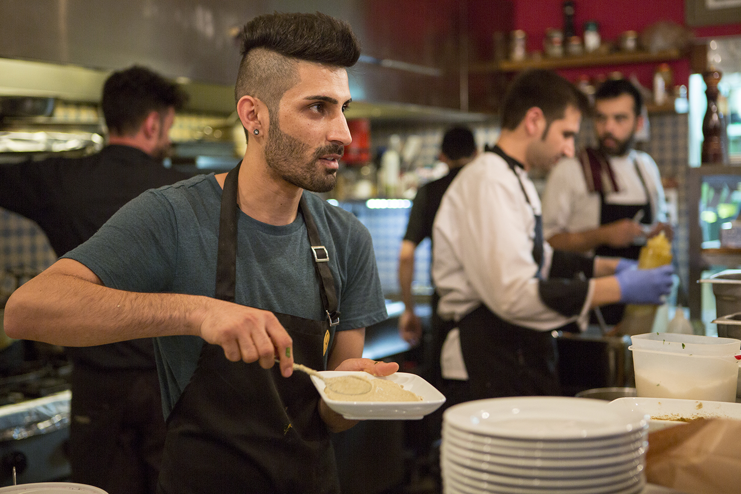 Syrian cook, Barshank Haj Younes, is preparing his dishes in the kitchen of a crowded restaurant in central Athens. 