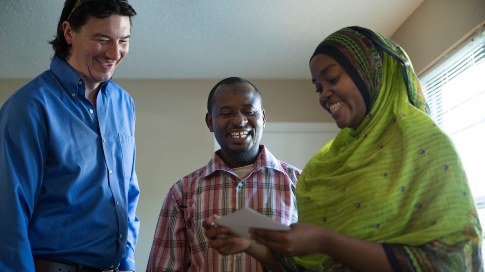 Cobi Cogbill looks at family photos with Majidi and his wife, Rehema, at Majidi and Rehema's apartment in Fayetteville, Arkansas.