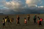 Rohingya families make their way across the beach at Dakhinpara, Bangladesh, after crossing the sea on fishing boats from Myanmar.