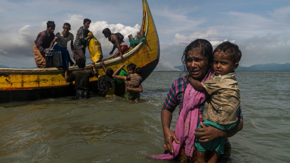 A mother carrying her child wades towards the beach at Dakhinpara, Bangladesh.