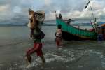 A Rohingya man carries a package towards the beach at Dakhinpara, Bangladesh.