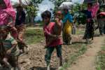 A Rohingya boy carries his little brother as he crosses with his family into Whaikhyang, Bangladesh.