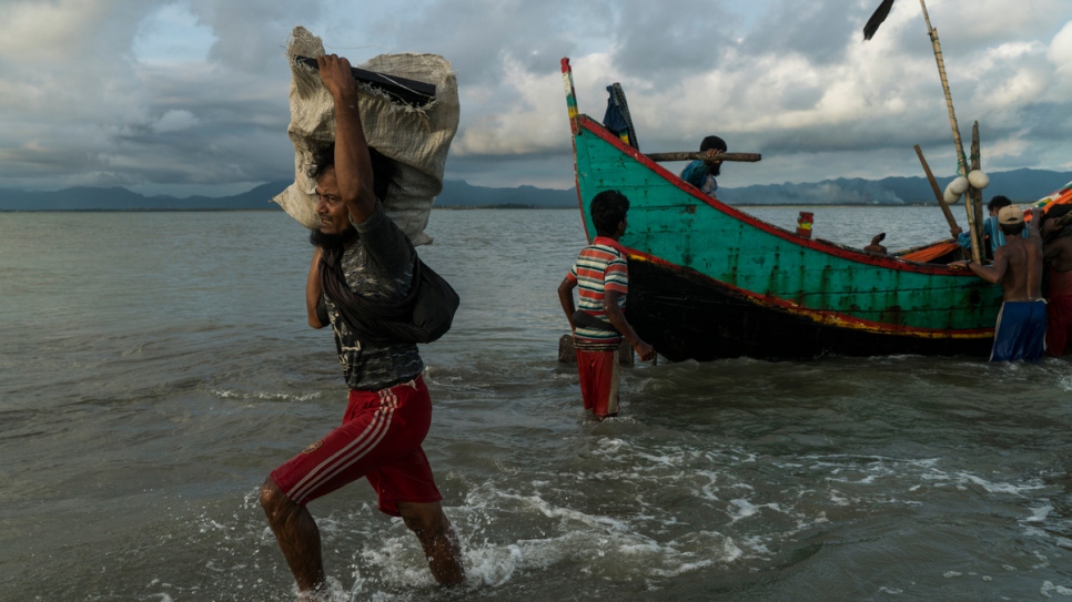 A Rohingya man carries a package towards the beach at Dakhinpara, Bangladesh.