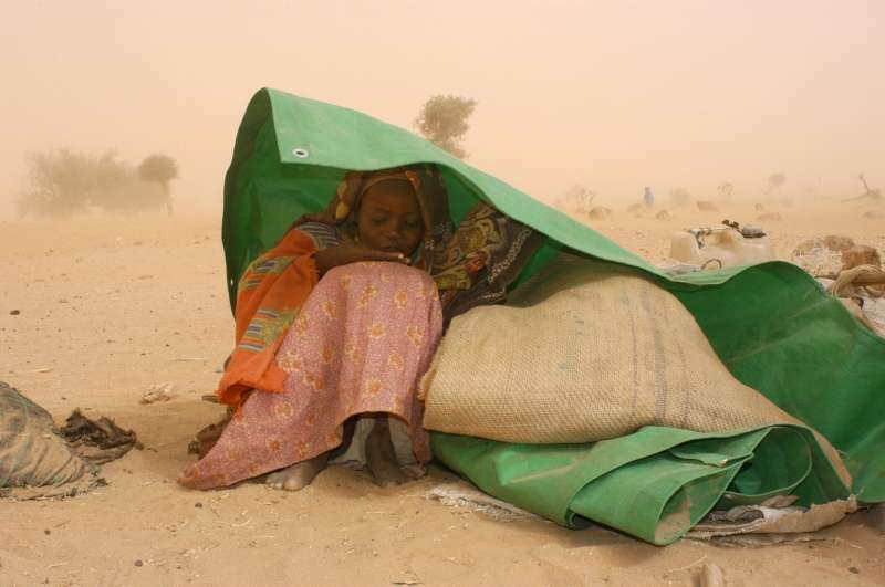 A Sudanese refugee seeks shelter from a sandstorm near the Chadian border town of Tine. (February 7, 2004)