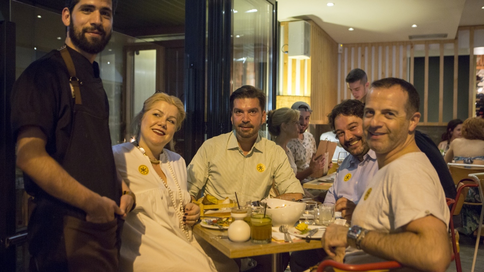 Le chef afghan réfugié, Reza Golami, pose avec des clients du restaurant 'It' d'Athènes, le 22 juin 2017, où il cuisine à l'occasion du Refugee Food Festival. 