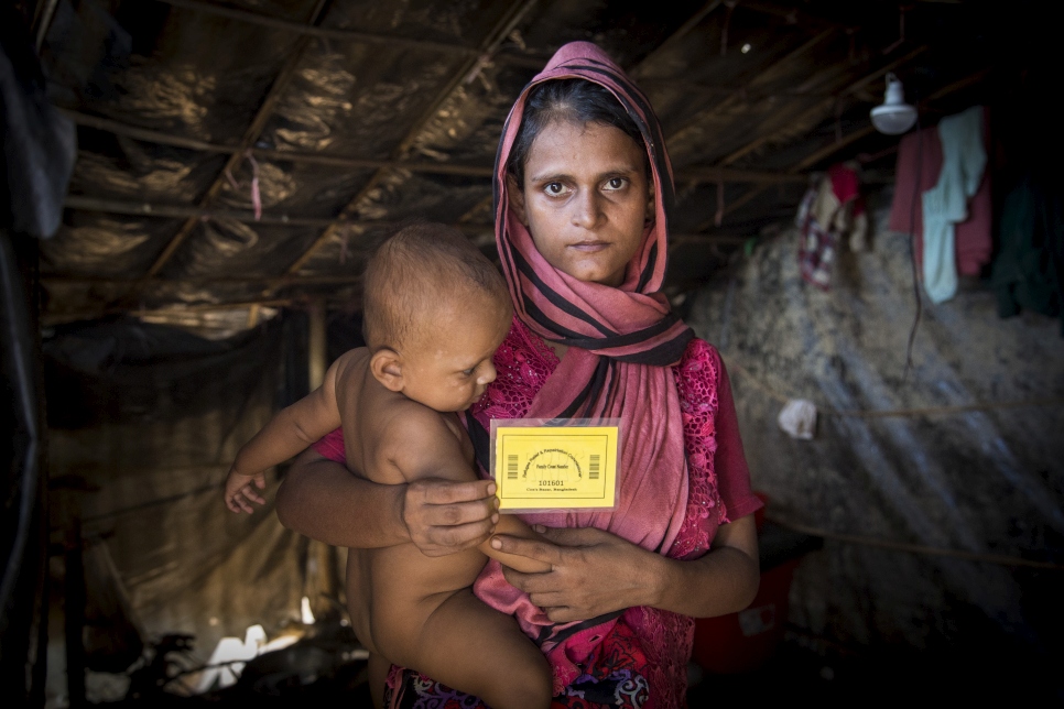 A Rohingya mother holds up the card given to her by UNHCR volunteers collecting information using a data-gathering smartphone app at the Kutupalong extension site. 