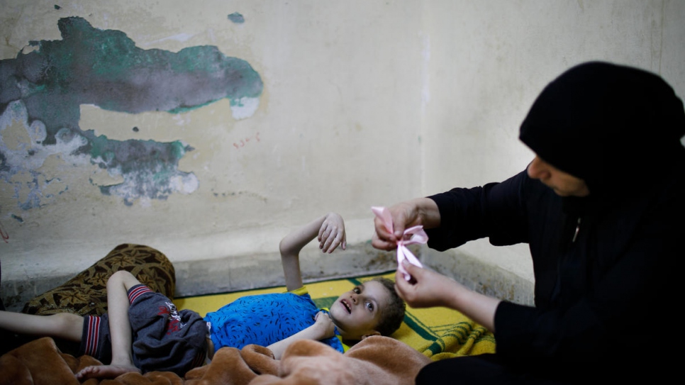 Ghania Hamweh, réfugiée syrienne, joue avec son fils Abdul Hadi chez eux, dans le camp de réfugiés d'Al Hussain, en Jordanie. Ghania a trois enfants qui souffrent de paralysie cérébrale et d'épilepsie. Elle a reçu deux sachets de gateaux sablés.