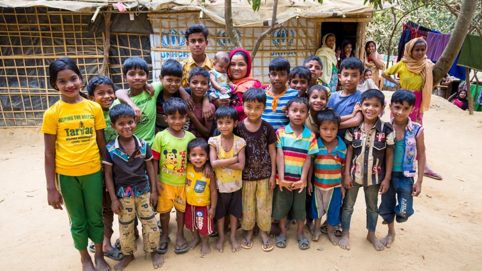 Khaleda Begum (foulard rouge) chez elle entourée d'enfants réfugiés qui vivent désormais sur les terres de sa ferme. 
