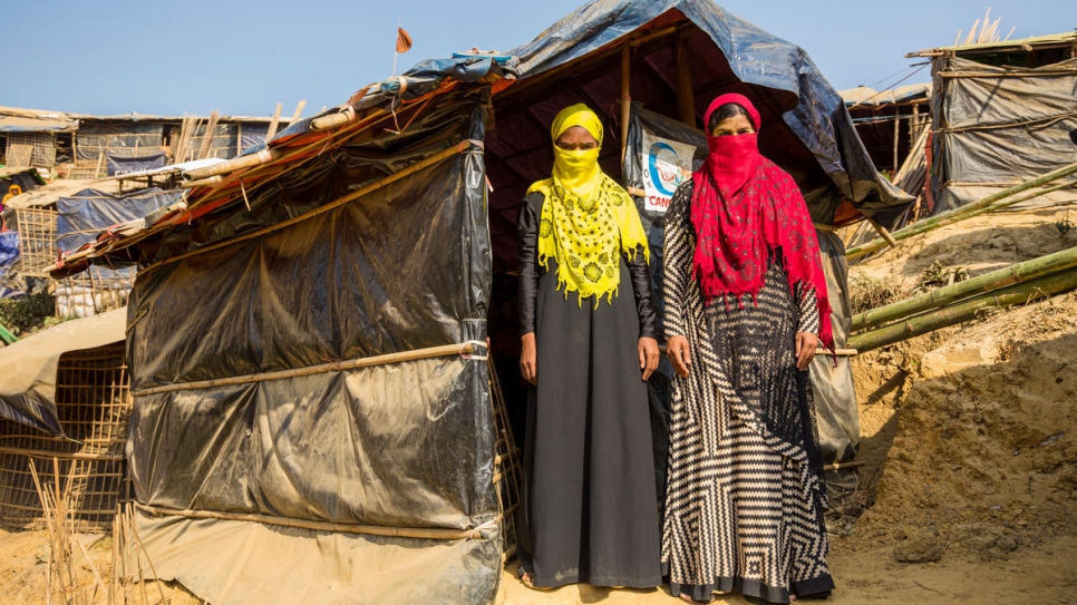 Mabia, left and  Shamshidah, right, stand outside their borrowed shelter at Kutupalong refugee settlement in Bangladesh.

