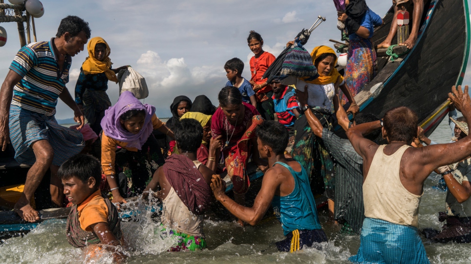 Rohingya refugees scramble off a boat arriving in Bangladesh from Myanmar as it lands on a beach in Dakhinpara, Bangladesh, on September 14 2017.