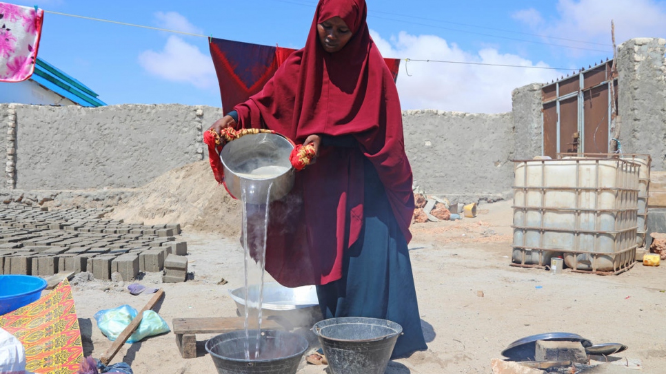 Without running water, Fadumo carries buckets back and forth to add water to her dyes.