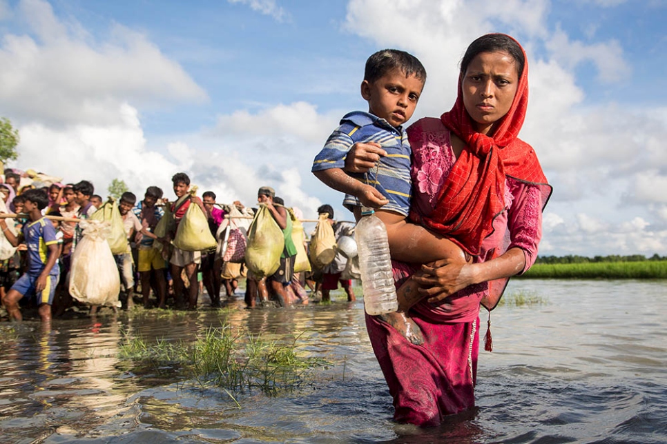 A Rohingya mother wades through water as she crosses the border from Myanmar into Bangladesh, near the village of Anzuman Para in Palong Khali.