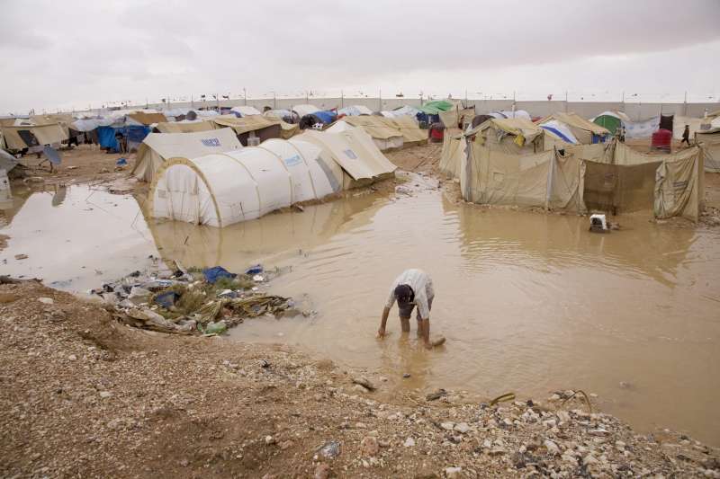 A Palestinian man wades through flood water in search of lost belongings. Severe rainstorms in October 2008 left tents inundated with water and sewage at Al Tanf, a settlement in the narrow no man's land between Iraq and Syria. 
