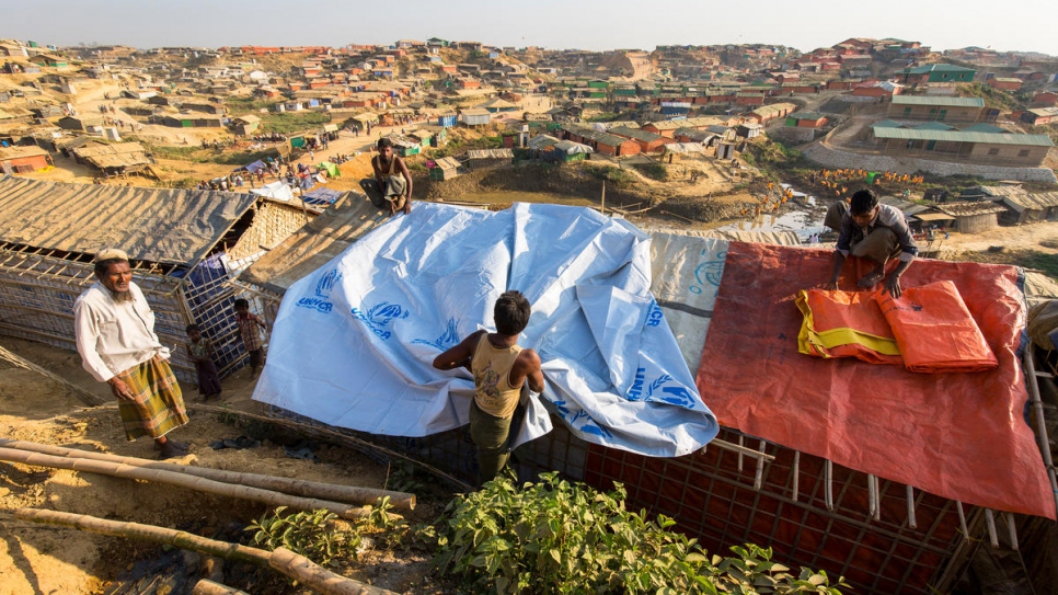 Un réfugié renforce un abri avec une bâche fournie par le HCR dans le camp de réfugiés de Kutupalong, au Bangladesh. 