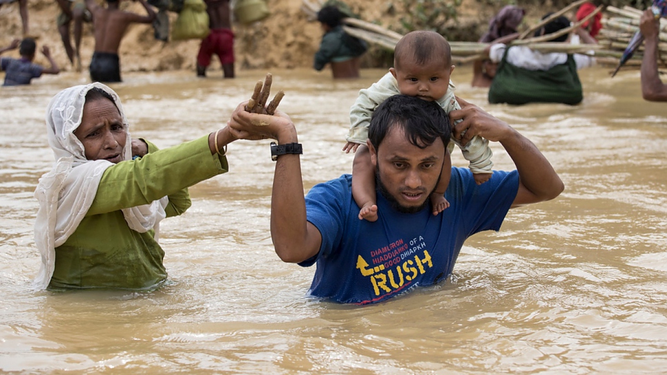 Une famille de réfugiés rohingyas en provenance du Myanmar traversant une rivière en crue après les pluies de la mousson de 2017 à Kutupalong, au Bangladesh.