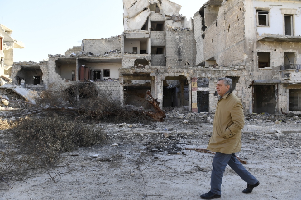 المفوض السامي للأمم المتحدة لشؤون اللاجئين، فيليبو غراندي، يسير أمام مبانٍ متضررة بشدة في حي كرم الميسر في شرق حلب، وذلك خلال زيارة قام بها لسوريا في فبراير2017.