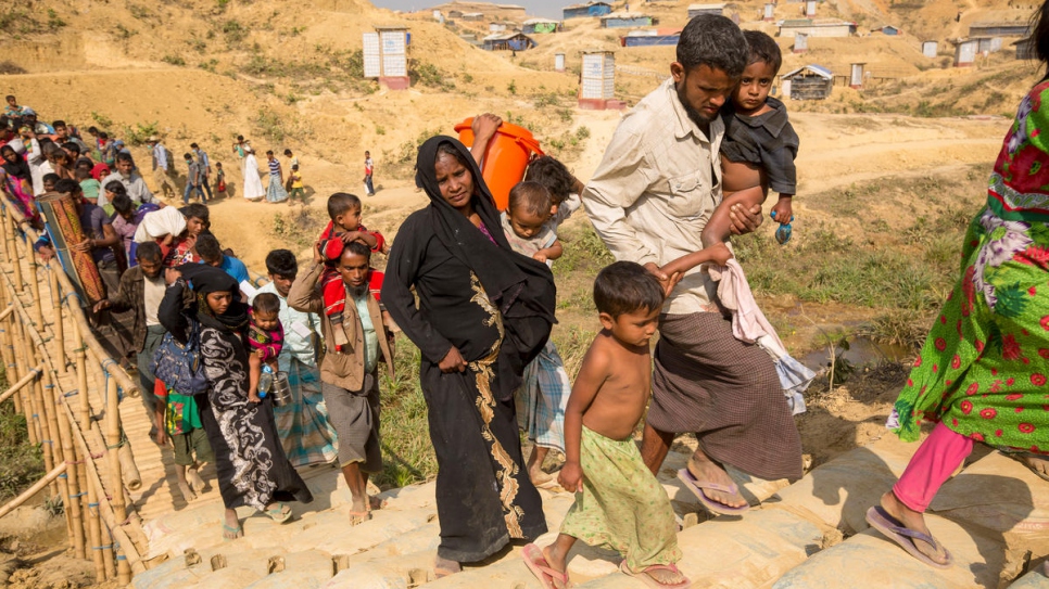 Mohammad Harez y Momena Begum caminan con sus hijos a un nuevo albergue en un terreno elevado en el asentamiento de refugiados de Kutupalong, Bangladesh.