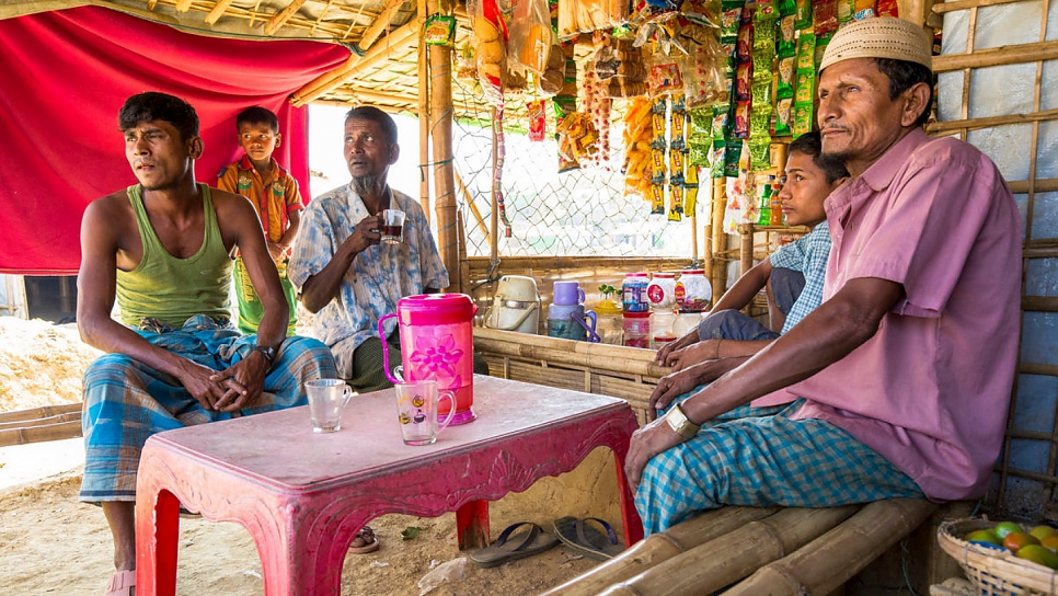 Mohammad Islam (en el centro) toma el té en el puesto de Kabir Ahmed (a la derecha) y su hijo Nur Mohammad (a la izquierda) en el asentamiento para refugiados de Kutupalong, en Bangladesh.