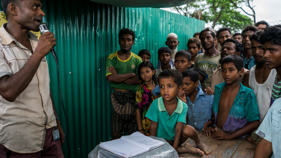 Un voluntario utiliza un altavoz para tratar de localizar a la familia de un niño de cuatro años (centro) en una cabina de información financiada por el ACNUR en el Campamento de Refugiados de Kutupalong, en Bangladesh.