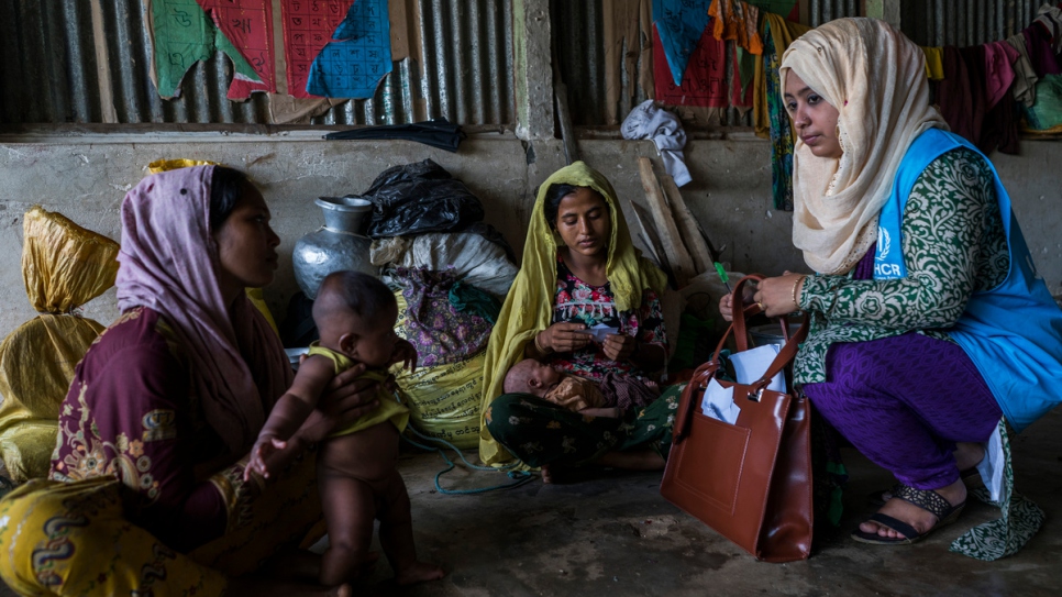 Hosna Ara Begum, de 30 años, trabajadora de ACNUR, habla con refugiados rohinyá recién llegados en la escuela primaria College Hill, acondicionada como albergue, en el Campamento de Refugiados de Kutupalong.