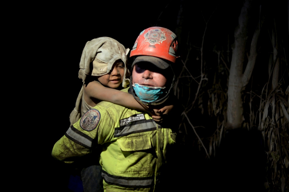 Un secouriste porte un enfant couvert de cendres suite à l'éruption du volcan de Fuego  El Rodeo, Guatemala. 