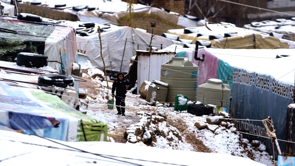 A young Syrian refugee walks through snow at an informal settlement in Lebanon's Bekaa Valley.