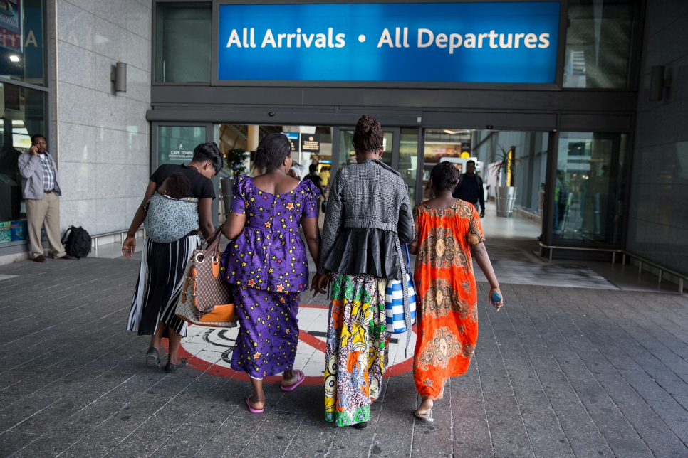 La réfugiée congolaise Bora Riziki (deuxième à droite) arrive à l'aéroport international du Cap avec ses amis, en route pour être réinstallée en France.