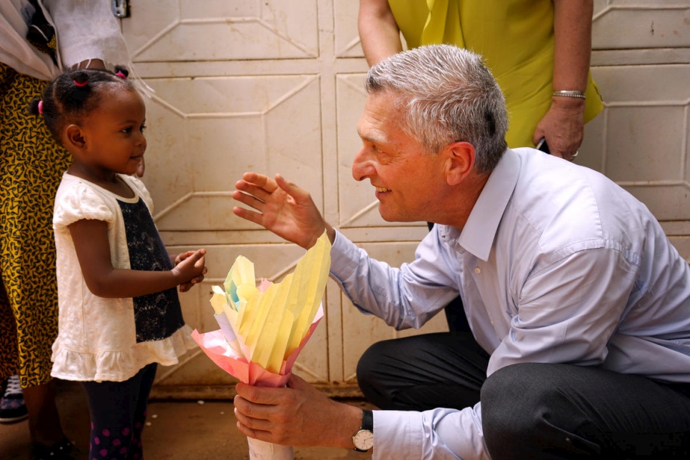 UN High Commissioner for Refugees Filippo Grandi (right) crouches to speak with a young refugee girl.