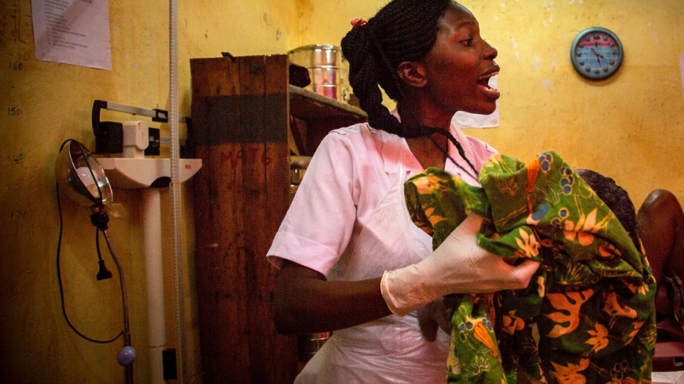 Cresencia, une infirmière tanzanienne de 22 ans, emporte la petite Marian pour la peser. 