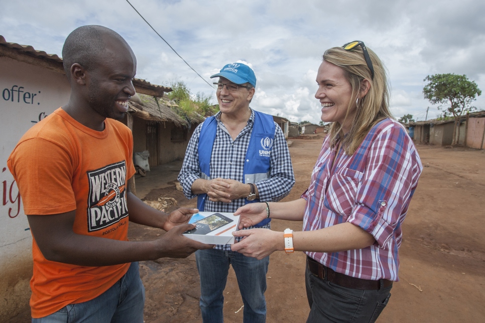 Remy Gakwaya, un jeune réfugié burundais de 22 ans reçoit un téléphone de la part de Kate Krukiel, Directrice des partenariats chez Microsoft, et de Kamel Deriche, du HCR. Le téléphone est un don de Microsoft qui soutient le projet de connectivité numérique pour les réfugiés dans le camp de Dzaleka, au Malawi. 