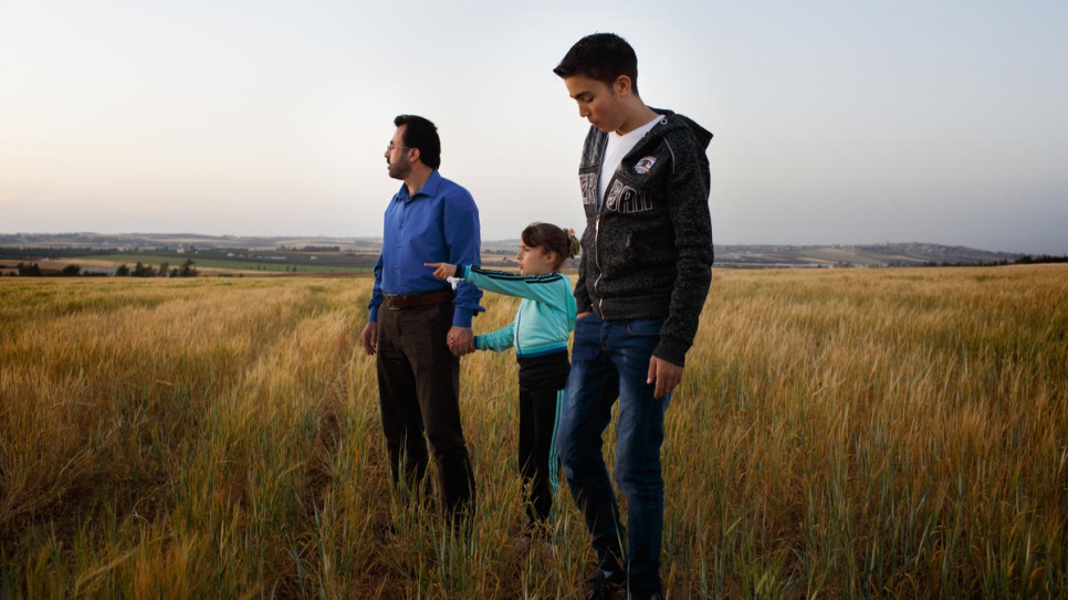 Hamed Mifleh, un réfugié syrien âgé de 47 ans (à gauche), se promène avec ses enfants, Ahmad (21 ans) et Bara'a (7 ans), dans un champ situé à proximité de leur maison, à Madaba. 