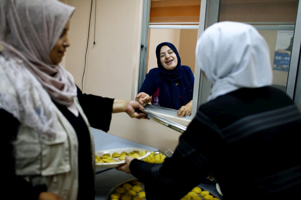 نجوى البدور (في الوسط) مديرة مركز الأميرة بسمة للتنمية الاجتماعية، تتفاعل مع الطاهيات الأردنيات واللاجئات اللواتي يصنعن المعمول، في عمان، الأردن.