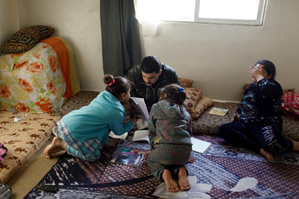 بعد عودته من المصنع، يساعد اللاجئ السوري محمد جمال كبور، 33 عاماً، ابنتيه على أداء واجبتهما المنزلية. 
