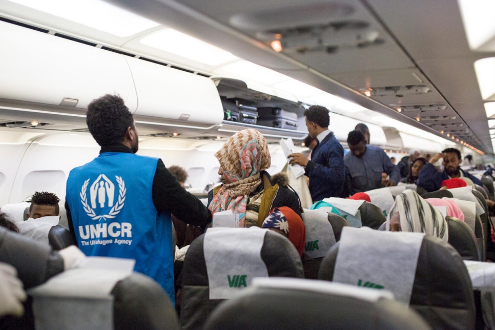 موظفو المفوضية يساعدون اللاجئين الضعفاء بينما يغادرون الطائرة.