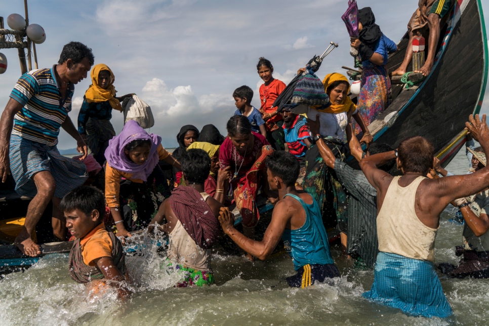 لاجئون من الروهينغا يتدافعون خارج قارب أتى إلى بنغلاديش من ميانمار عندما وصل إلى الشاطئ في داخينبارا، في بنغلاديش في 14 سبتمبر 2017.
