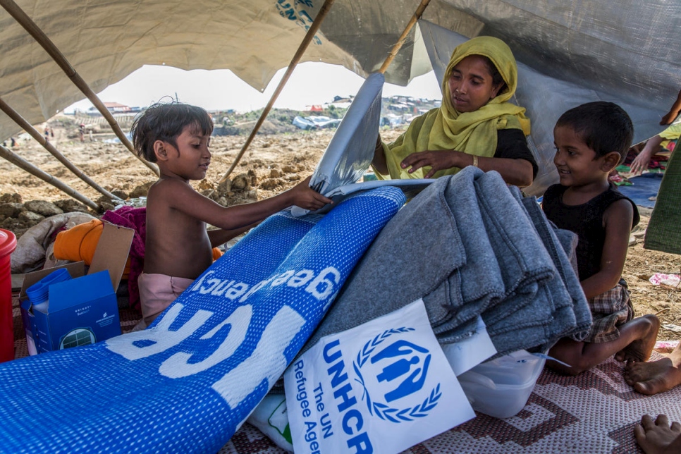 ليلى بيغوم، 30 عاماً، وأطفالها يفتحون حزمة مساعدات، بما في ذلك مصباح يعمل على الطاقة الشمسية وشاحن للهاتف وبطانيات وأقمشة مشمعة ولوازم مطبخية، في مخيم اللاجئين في كوتوبالونغ في 20 نوفمبر.