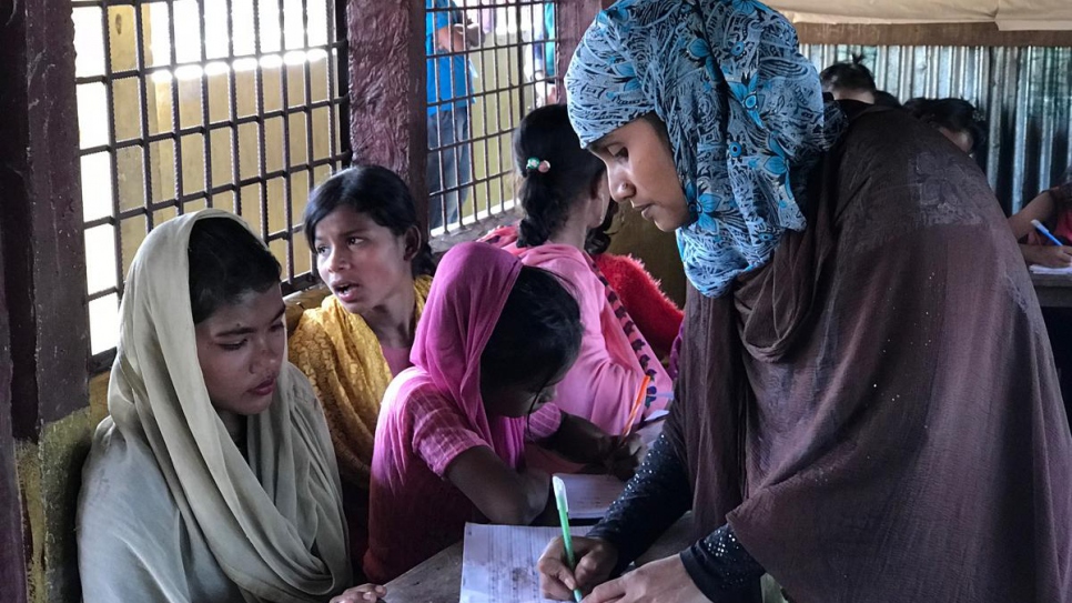Rohingya refugee teacher Alinesa, 32 (one name only) marks the work of pupil, newly arrived refugee, Rosina Akhter, 12.