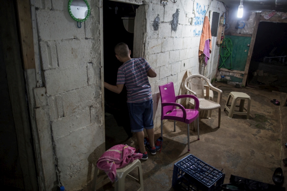 محمد، 10 أعوام، ينظر إلى شقيقه الأصغر عصام، 8 أعوام، نائماً في غرفته في منزل العائلة المؤقت في الجية، لبنان.
