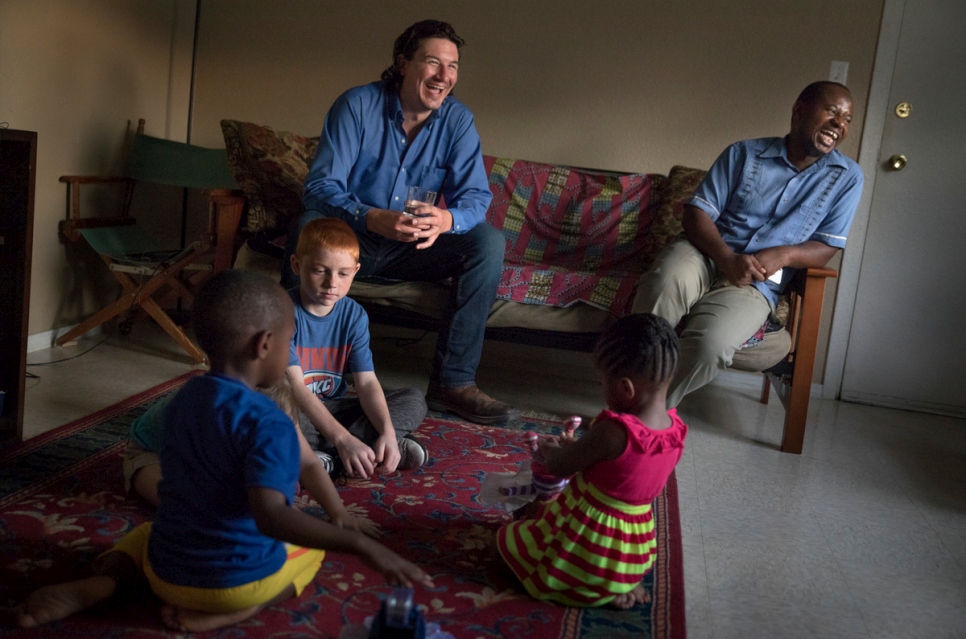 كوبي كوغبيل، 31 عاماً، (إلى اليسار)، ومجيدي، 36 عاماً، يجلسان مع أطفالهما الذين يلعبون معاً في منزله في فايتفيل، أركنساس. أصبحا أفضل صديقين منذ أول لقاء.