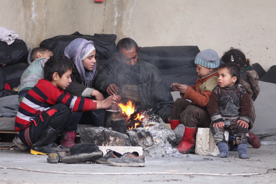 A family displaced from their homes in east Aleppo try to keep themselves warm around a fire in the Jibreen industrial zone of the city, where warehouse buildings have been converted into temporary accommodation for thousands of people.