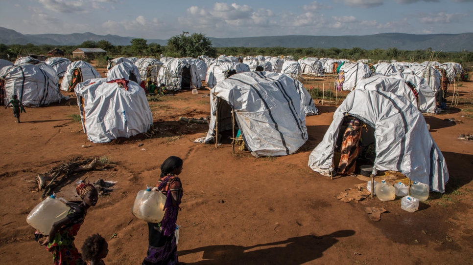 Women carry water to their temporary shelter at a refugee camp in Sololo, Marsabit County in  Kenya.